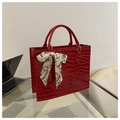 Dettaglio borsa rossa con trama a coccodrillo e foulard di seta decorativo sul manico - Rosso