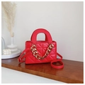 Close-up of red quilted handbag featuring a bold gold chain and elegant top handle - Red