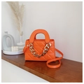 Detail of bright orange quilted bag with chunky gold chain and thin shoulder strap - Orange