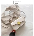 Details der weißen Leder-Umhängetasche mit goldener Schließe und plissiertem Wolkengriff - Weiß