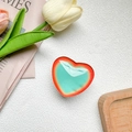 Detail of red and green gradient heart phone grip with glossy jelly texture on tray - White Base Stand / Crystal Glass Texture - Gradient Dual Tone