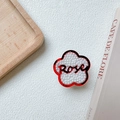 Détail du support téléphone en fleur rouge avec perles et texte Rose dans un décor - Support Fleur Perle-Rouge (Rose)