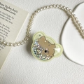 Dettaglio del supporto per telefono a forma di orso con paillettes e bordo verde - Orso Giallo