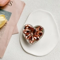 Dettaglio del supporto per telefono a cuore con strass e cristalli color ambra - Champagne