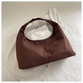 Close-up of brown suede shoulder bag with vertical stitching on a white shirt background - Brown