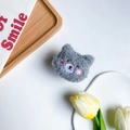 Detalle de un soporte para móvil de osito de peluche gris suave con bordados finos - Oso de Mejillas Rosadas / Gris