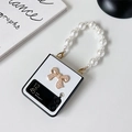 Detail of white textured Z Flip case with golden metal bow and pearl handle chain - Pearl Bow with Pearl Chain (White) / White / Samsung ZFlip3