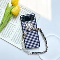 Detalle de funda Z Flip de pata de gallo con flor de camelia y cadena de cuero y perlas - Blanco / Samsung ZFlip5