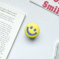 Close-up of yellow telescopic phone grip with blue smiley face on a stylish background - Yellow