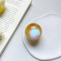 Macro shot of glitter amber phone grip with blue-purple laser holographic effect on white tray - Yellow