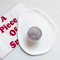 Transparent round phone griptok with pink and purple glitter on a white tray - Jelly Grey