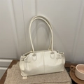 Minimalistische cremeweiße glänzende Leder-Tote-Tasche auf einer gemütlichen Strickdecke - Gebrochenes Weiß