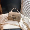 Minimalist khaki trapezoid crossbody bag with metal twist lock on a white suit jacket - Khaki