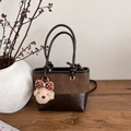 Vintage brown leather bucket bag with plush bear charm on a minimalist wooden table - With Pendant / Brown