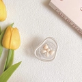 Detail view of a wavy clear acrylic hair claw clip with a cream bow on a soft white cloth - Pearl Circle Stand - Gradient Bow