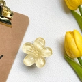Dettaglio del supporto per telefono a fiore giallo con glitter dorati su pelle bianca - Giallo