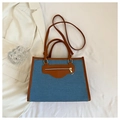 Dettaglio della borsa tote in denim con finiture in pelle marrone, cerniera e tracolla - Azzurro