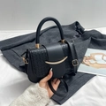 Borsa nera chic con patta intrecciata e fibbia dorata su un blazer grigio - Nero