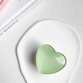 Dettaglio di un supporto per telefono a forma di cuore verde chiaro su vassoio bianco - Supporto a Base Bianca / verde chiaro