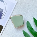 Detalle del soporte para móvil verde claro con borde plateado en fondo texturizado - verde claro