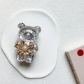 Detailed view of bear phone grip with colorful sequins and small golden flower accessory - Silver