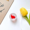 Close-up of a clear heart-shaped phone grip with a red heart and a yellow tulip - Red