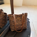 Borsa tote leopardata con manici in pelle marrone su sfondo di un blazer nero - Piccolo Leopardo Marrone