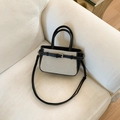 Dettaglio borsa coreana in tela beige e pelle nera appoggiata su un divano - Nero