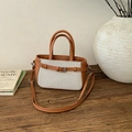 Dettaglio della borsa in tela e pelle a contrasto su una superficie in legno vintage - Marrone