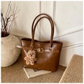 Détail d'un sac cabas marron en similicuir avec boucles métalliques et pendentif en peluche - Avec Pendentif / Marron
