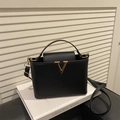 Classic black pebbled leather handbag featuring a signature gold V buckle and top handle - Black