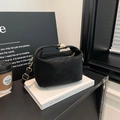 Bolso de hombro retro negro mate con herrajes dorados sobre un libro blanco elegante - Negro
