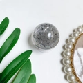 Detail of clear crystal ball phone grip with silver foil flakes on white surface - Grey (Silver Foil)