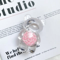 Makro-Detail des transparenten Bären-Handyhalters mit rosa Spirale auf einer Zeitschrift - Lollipop Rosa Bär / Rosa