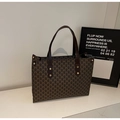 Dettaglio della borsa tote vintage marrone con stampa monogramma M e rivetti in metallo - caffè
