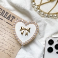 Dettaglio di un supporto per telefono a cuore con fiocco dorato e perle su tessuto bianco - Fiocco a Cuore in Metallo - Bianco / Bianco