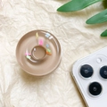 Macro shot of 3D donut phone grip with colorful sprinkles on beige paper background - Brown