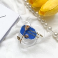Dettaglio del supporto per telefono a cuore con rosa dorata e centro blu su tessuto - Blu