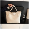 Close-up of the beige pebble leather tote bag featuring a metallic logo and sturdy handles - White