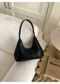 Detalle de bolso hobo negro texturizado en sofá con acabado brillante vintage y cremallera - Negro