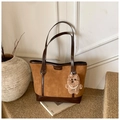 Detailed close-up of brown suede tote bag with logo embossing and plush bear charm - Brown With Pendant