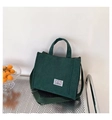 Dettaglio della borsa tote in velluto a coste verde scuro con tracolla e etichetta vintage - Verde