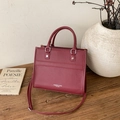 Elegant burgundy tote bag with leather texture and top handles on a wooden table - Red
