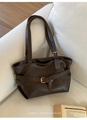 Close-up of retro dark brown tote bag with leather straps and metal buckles on a sofa - Brown