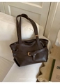 Detail of a vintage dark brown tote bag with gold buckle on a soft white fabric sofa - Coffee