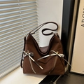 Borsa tote marrone con fiocchi e doppie cerniere su un davanzale con ombre di luce - Marrone