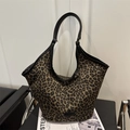 Bolso tote de lona con estampado de leopardo y asas de cuero negro en silla blanca - Estampado de leopardo