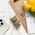 Detailed view of a brown cute bear-shaped expandable phone socket on a white fabric background - Brown