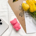 Pink bear socket grip for phone back shown with yellow tulips on textured white fabric - Red