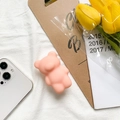 Close-up of cute pink bear pop socket phone holder on white fabric with tulips - Orange